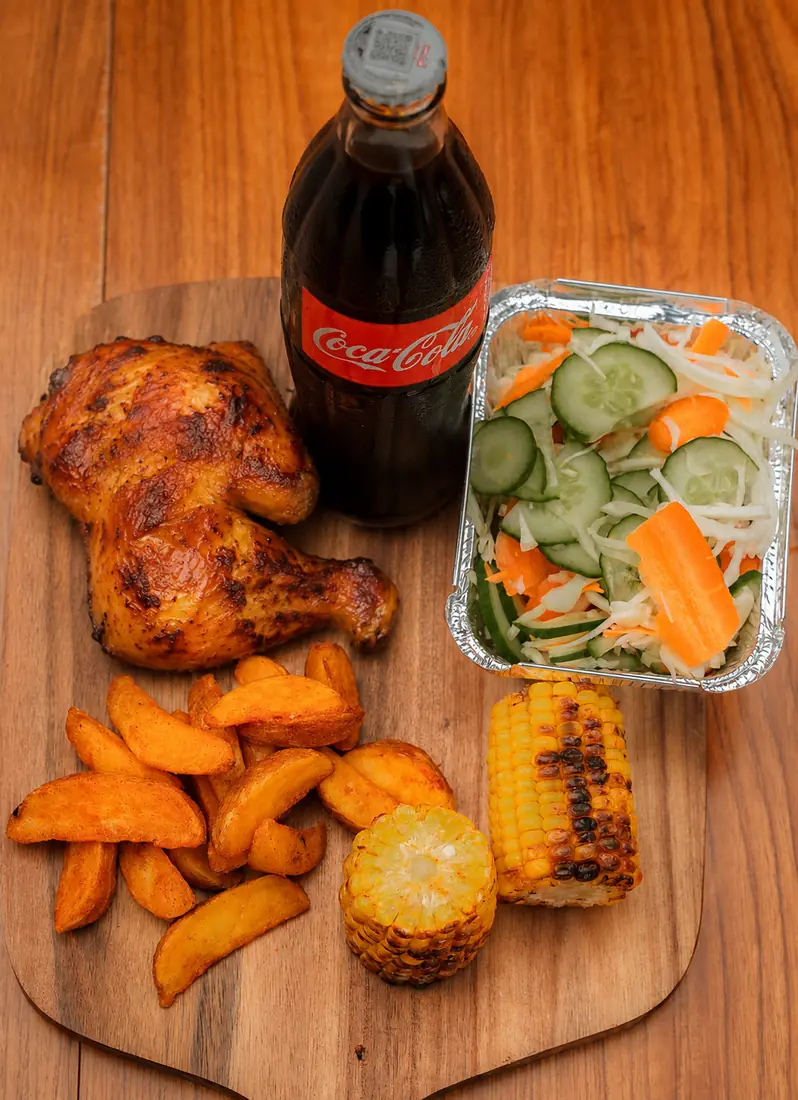 BBQ chicken meal with potato wedges, salad, roasted corn, and Coke